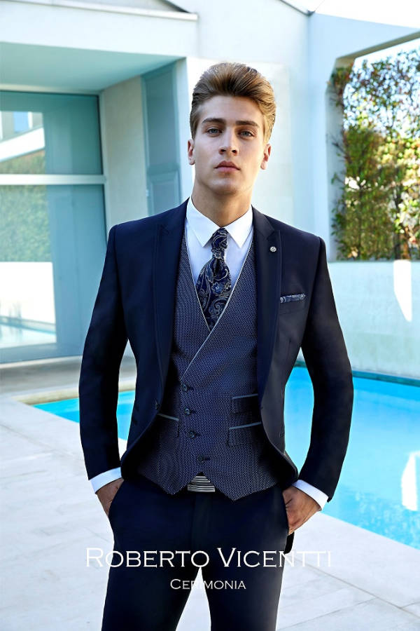 Junger Mann in Herrenmode Dolce Vita Roberto Vicentti blauer Anzug mit Krawatte neben Pool